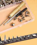 Close-up of Dope 550 Piece Punk Studs And Spikes Kit with conical studs, tools, and accessories on leather and in a box.