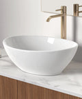 Premium Oval Ceramic Vessel Sink For Bathroom Vanity Countertop Glossy White Porcelain Bowl Above Counter on marble surface.