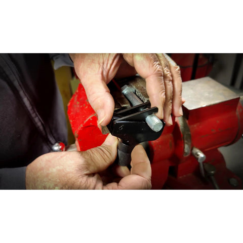 Powerbuilt Universal Thread Repair Tool, black metal, held by hands beside a red bench vise.