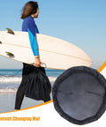 No Fuss Surf And Swim Changing Mat With Waterproof Sandproof Wetsuit Dry Bag shown by surfer on beach with surfboard