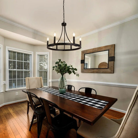 Six Light Wagon Wheel Chandelier In Black Industrial Farmhouse Style hanging over dining table in bright room