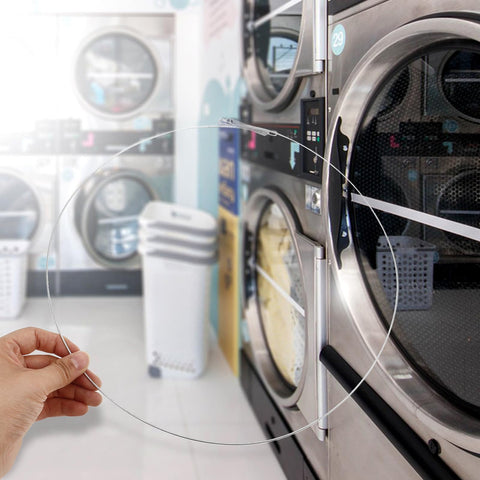 Hand holding Stainless Steel Washing Machine Door Boot Spring Clamp For Front Load Washers near a washer in a laundromat.