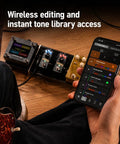 Musician using phone to control Tonex One Plus AI Guitar Amp And Effects Pedal with Bluetooth, shown on wooden floor.
