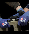 Workers wearing AeroDex 18 Gauge ANSI A5 Cut Resistant Work Gloves with Foam Nitrile Palm Coating, handling concrete block.