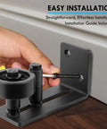 Sliding Barn Door Floor Guide With Bottom Adjustable Roller Eight Setup Options Delivers Quiet Operation And A Flush Design With Felt Strips Prevents Door From Swinging Or Hitting Walls Ensures Perfect Alignment Easy Installation Pack Of One is being installed on a floor surface.