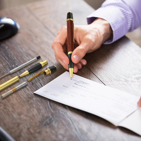 Person writing with 12 Pack Woodturning Pen Kit With Twist Ballpoint Refills Copper Turning Supplies on wooden desk