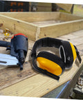 Lock Down Every Distraction Heavy Duty Noise Reduction Earmuffs on a workbench with a nail gun, ideal for industrial use.