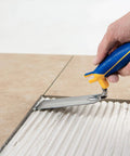 Person using Comfort Grip 6 In By 2 In Flat Margin Flooring Trowel With Bucket Hook on thinset between tiles.