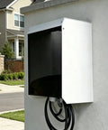 Top Shelf Electric Vehicle Charger Cover Box Crafted From Solid Galvanized Steel Featuring Magnetic Acrylic Panel For Wall Mounted Outdoor Charging Stations Weather Tight Enclosure That Handles Any Damn Weather mounted on a wall with charging cable.