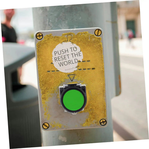 Street button labeled 'Push to Reset the World', mounted on a pole with a bright green push surface.