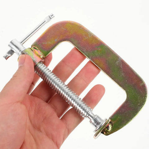 Hand holding a Heavy Duty 2 Pack Small Metal G Clamp 3 Inch Tabletop Woodworking Clamp For Desk Mounting And Woodworking Fixing Built Tough For DIY Projects Beast For Carpentry Metalworking And Crafts