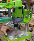 Beefy 710W Mini Drill Press with Cast Iron Base in action on a workbench, showing hands operating the drill on metal