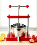 Heavy Duty Manual Fruit Wine Press Built Like A Tank Food Grade Stainless Steel Apple Grape Juicer on wooden table with lemons and strawberries.