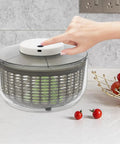 Game Changing Hella Big Electric Salad Spinner For Quick Lettuce Washing Knockout Battery Powered Produce Dryer with user pressing button.
