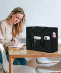 Woman studying at a table with Ultra Large Waterproof Tote Bag For Women With 12 Pockets And Top Zipper Closure beside her.