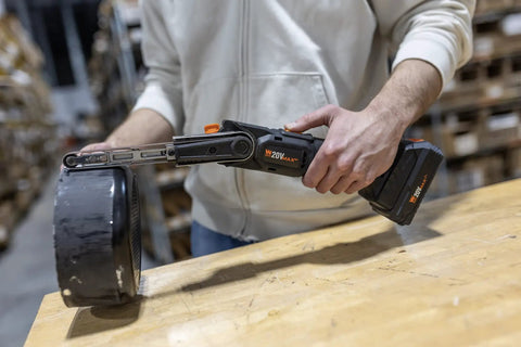 Cordless Detail File Sander With Variable Speed 1000 To 1600 FPM Auto Tracking Belt in use on wooden table in workshop