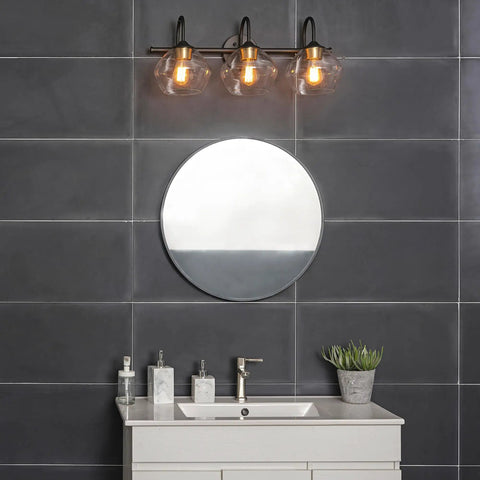 Lofty Chic Three Light Vanity Light In Dark Bronze With Clear Glass Shades And Antique Brass Accents over bathroom mirror