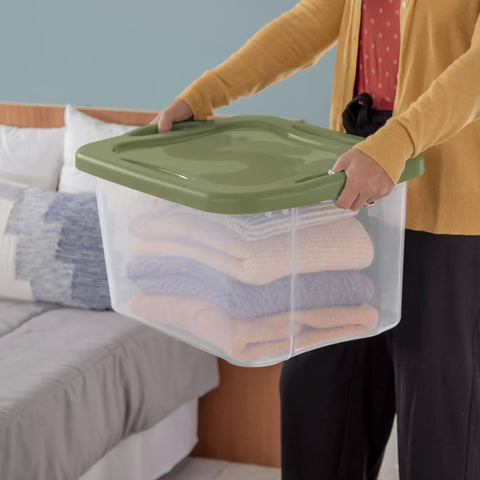 Person holding Heavy Duty 2 Pack 40 Quart Clear Plastic Storage Bins Stackable Totes with blankets inside.