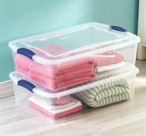 Heavy Duty 32 Quart Medium Clear Plastic Latching Storage Bin With Snap Tight Locking Lid holding folded towels in a home setting.