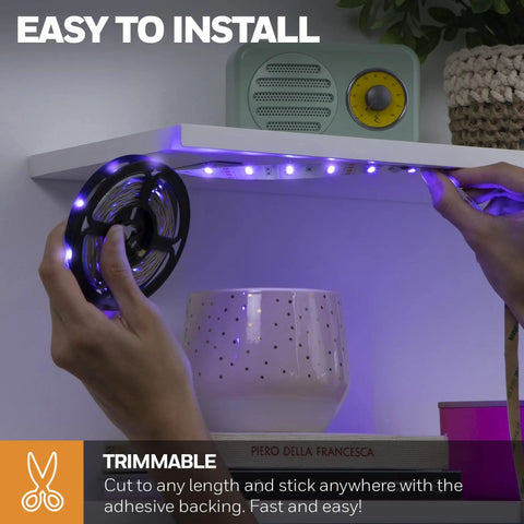 Hands installing Color Changing RGB LED Strip Light 16.4 Ft With Motion Sensor And Remote under a shelf with adhesive backing.