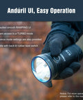 Person holding Beast Mode 18,000 Lumen Tactical Flashlight With 3 XHP70.2 LEDs in a gloved hand, showcasing Anduril UI interface.