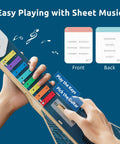 Hands holding DIY Electronics Guitar Building Kit for Kids 8-12 with sheet music cards, showcasing colorful keys and wooden body.