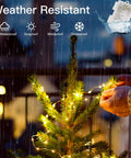 Person decorating a small outdoor Christmas tree in rain with 200 LED Battery Operated Fairy Lights With Remote, 66Ft Silver-Coated Copper Wire