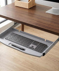 Heavy Duty Steel Under Desk Keyboard Tray Featuring Slick Ball Bearing Glides For Silky Smooth Extension And Rock Solid Ergonomic Workstation Support Up To Sixty Six Pounds With Zero Wobble Or Jamming Vibes installed under a wooden desk showing sleek gray design.