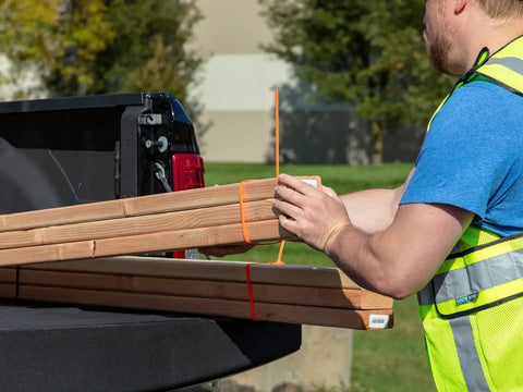 Heavy Duty Reusable Cable Ties With No Sweat Quick Release Lever securely holding wooden boards in a pickup truck bed.