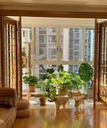 Sunlit living room with open bifold doors and indoor plants, showcasing Heavy Duty Bifold Closet Door Hardware Kit Fits 48 to 96 Inch Tracks.