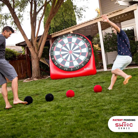 Two adults playing with Inflatable Giant Kick Darts Set With Jumbo Soccer Dartboard And Air Pump For Backyard Carnival Games