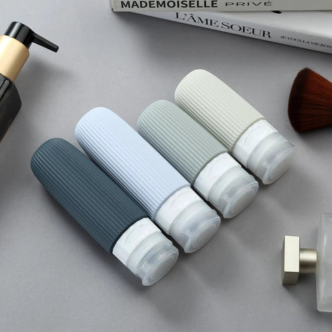 TSA Approved Travel Bottle Set With Leak Proof Silicone Squeezable Containers For Toiletries showing four bottles on a table.