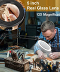 Person using Large 5 Inch Magnifying Glass With Light And Stand For Close Work And Soldering at a workbench, showing 12X LED magnifier in use.