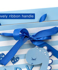 Close-up of Blue Dinosaur Baby Boy Gift Bag With Tissue Paper And Greeting Card Durable Ribbon Handles And Reinforced Bottom 13 By 10 By 5 Inches Perfect For Baby Showers New Parents And More, featuring a blue ribbon handle and dinosaur design.