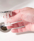 The Real Deal Drain Protector And Hair Catcher Combo For Bathtubs And Sinks Chrome Finish, hand holding sink strainer above drain.