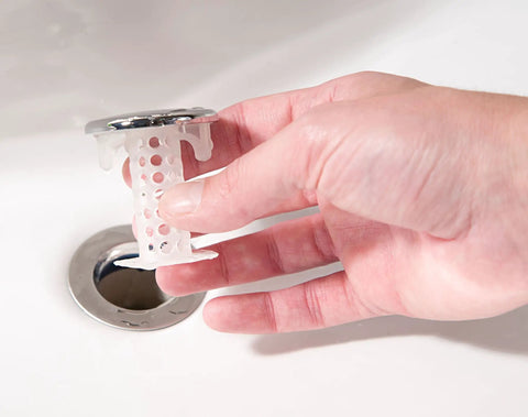 The Real Deal Drain Protector And Hair Catcher Combo For Bathtubs And Sinks Chrome Finish, hand holding sink strainer above drain.