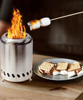 Smokeless Tabletop Fire Pit Outdoor Pellet Stove Mini Portable Bonfire with flames beside plate of marshmallow treats