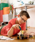 Boy assembling RC car using 9G Micro Servo Motor SG90 Metal Gear for Arduino and DIY projects in home workshop with electronic components