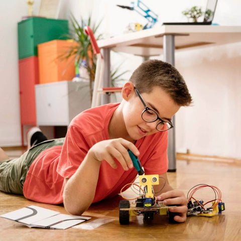 Boy assembling RC car using 9G Micro Servo Motor SG90 Metal Gear for Arduino and DIY projects in home workshop with electronic components