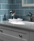 Claymore Single Hole Bathroom Faucet In Oil Rubbed Bronze With One Handle Includes Pop Up Drain Ceramic Disc Valve Easy Install For 1 Hole Or 3 Hole 4 Inch Configuration Slick Modern Look installed on a white vanity against blue tile wall.