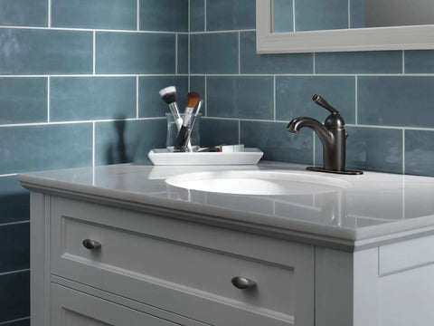 Claymore Single Hole Bathroom Faucet In Oil Rubbed Bronze With One Handle Includes Pop Up Drain Ceramic Disc Valve Easy Install For 1 Hole Or 3 Hole 4 Inch Configuration Slick Modern Look installed on a white vanity against blue tile wall.