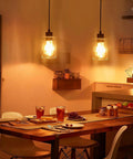 Two Pack Black Hammered Glass Pendant Lights With Adjustable Cords For Kitchen Island, illuminating a dining room table.