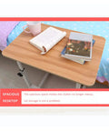 Adjustable Height Rolling Overbed Table With Easy Glide Casters For Bed Sofa Or Recliner Solid Sturdy Laptop Desk, spacious wooden surface with books and cup.
