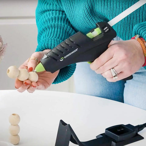 Person using Cordless High Temperature Glue Gun 60W With Standby Base And 380 Degrees F Bonding Power For Metal Wood Ceramics Leather And Other Tough Materials Full Size Pro Tool For Quick Strong Bonds on wood beads