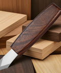 Dual Beveled Wood Marking Knife With Bombproof Beech Handle And Hella Sharp Vanadium Steel Core resting on assorted wood pieces.