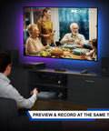 Man using VHS to digital converter and recorder with remote, converting video on a TV screen, plug and play, no PC needed.