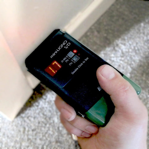 Hand using Pin Moisture Meter For Wood And Drywall Construction And Flooring With Auto Hold Humidity Detection For Water Damage