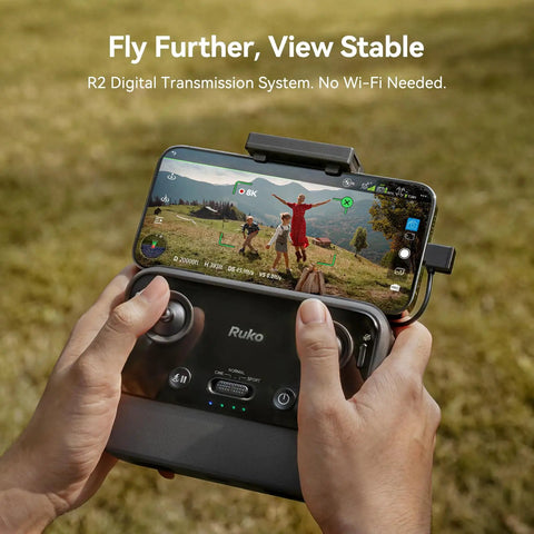 Hands holding remote of Ultra Portable Pocket Drone Under 249g With 4K Video And 8K Photo, FPV view of landscape on phone display.
