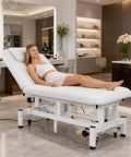 OmySalon Pro Electric Lift Massage Table With Dual Motors For Facial Beauty Salon Spa Therapy in sleek white with client.
