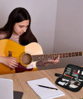 Person playing guitar with All In One 26 Piece Guitar Setup and Repair Kit with Carry Bag for Guitar Ukulele Bass Mandolin Banjo Tools visible.